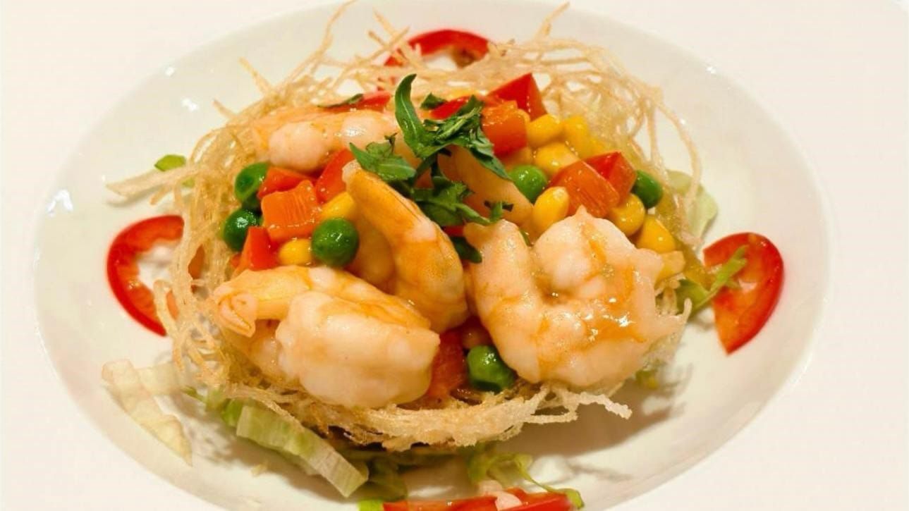 Insalata di gamberetti con verdure colorate tagliate a dadini ed erbe aromatiche, su un piatto bianco