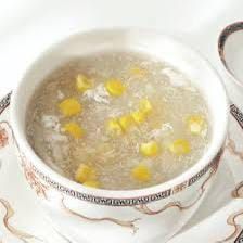 Una tazza da tè bianca con zuppa chiara e petali di fiori gialli su un piattino