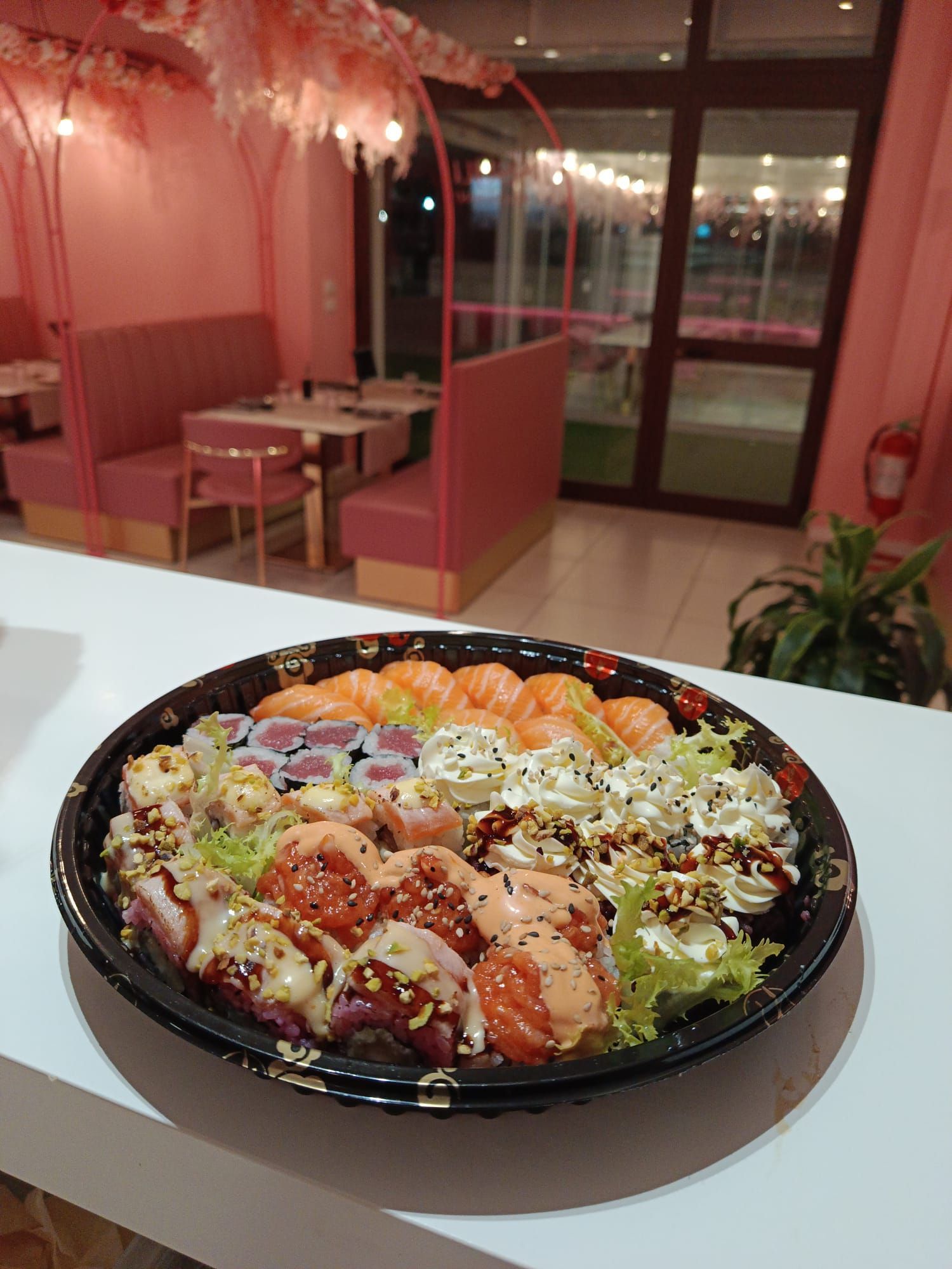 Grande vassoio di sushi su un tavolo in un tavolo di un ristorante illuminato di rosa