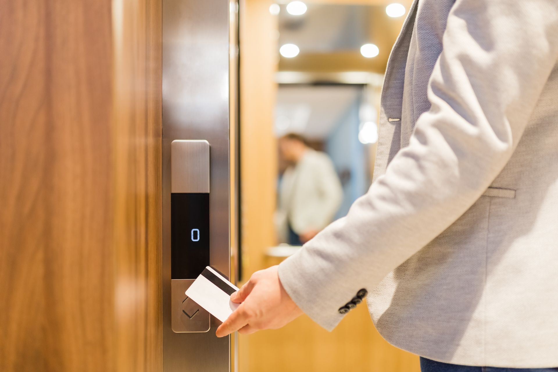 Person swipes key card by elevator door to access the elevator.