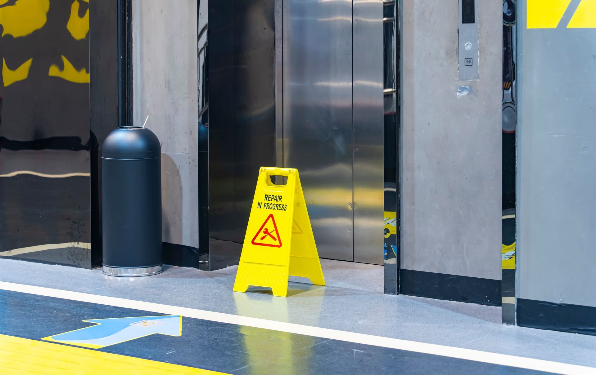 Yellow sign in front of an elevator. The floor is shiny and reflective. Yellow sign in front of an elevator. The floor is shiny and reflective.