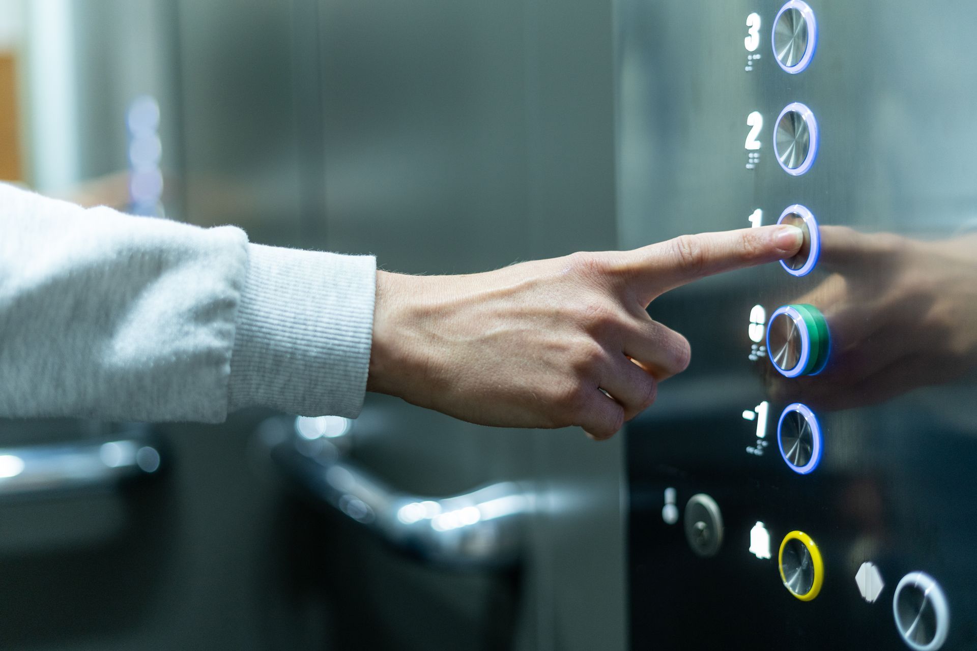 Person's finger pressing an elevator button to go to floor 1. Interior, buttons with illuminated blue halos. Person's finger pressing an elevator button to go to floor 1. Interior, buttons with illuminated blue halos.