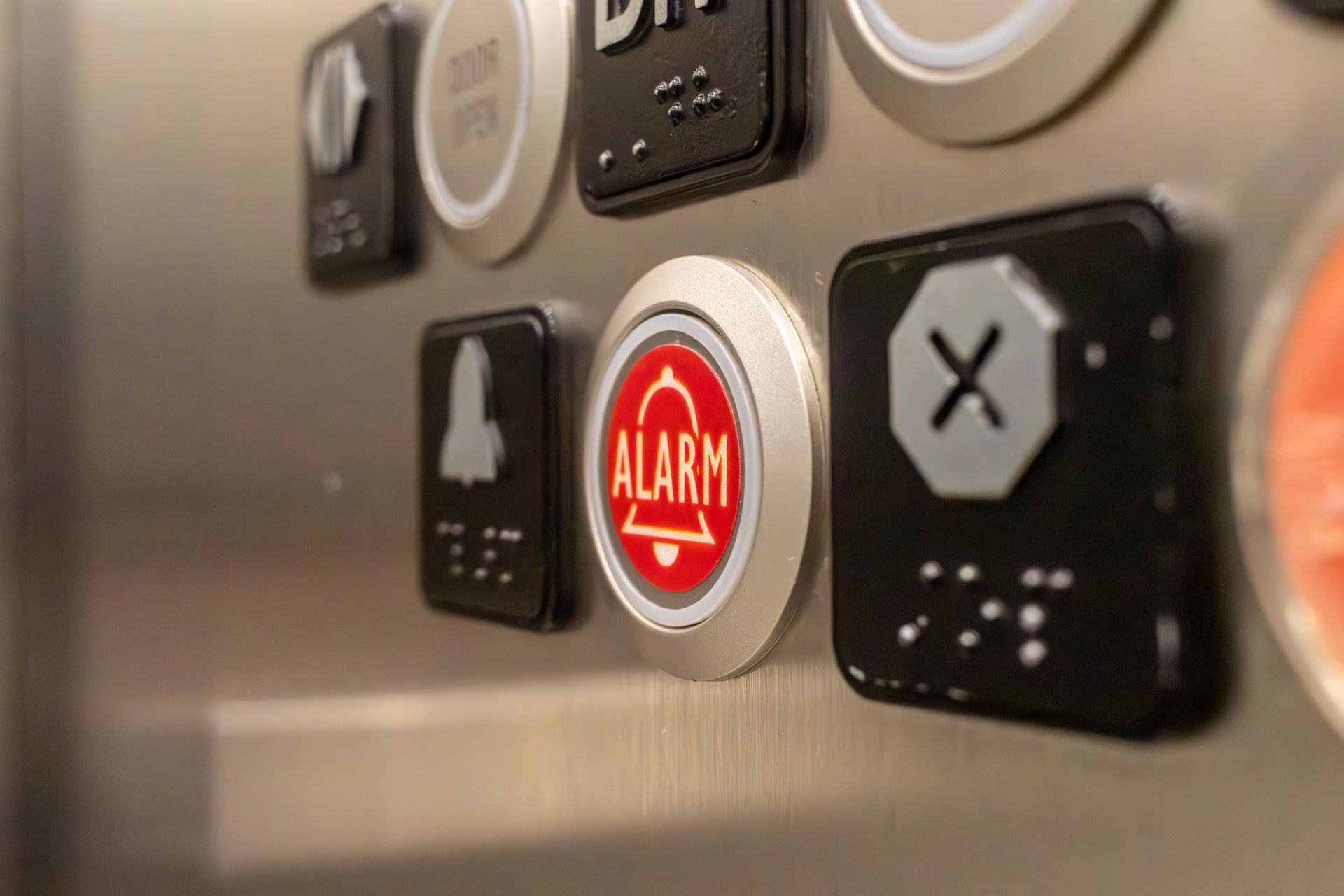 Elevator control panel with buttons, including door open, alarm bell, and a button with an X symbol.