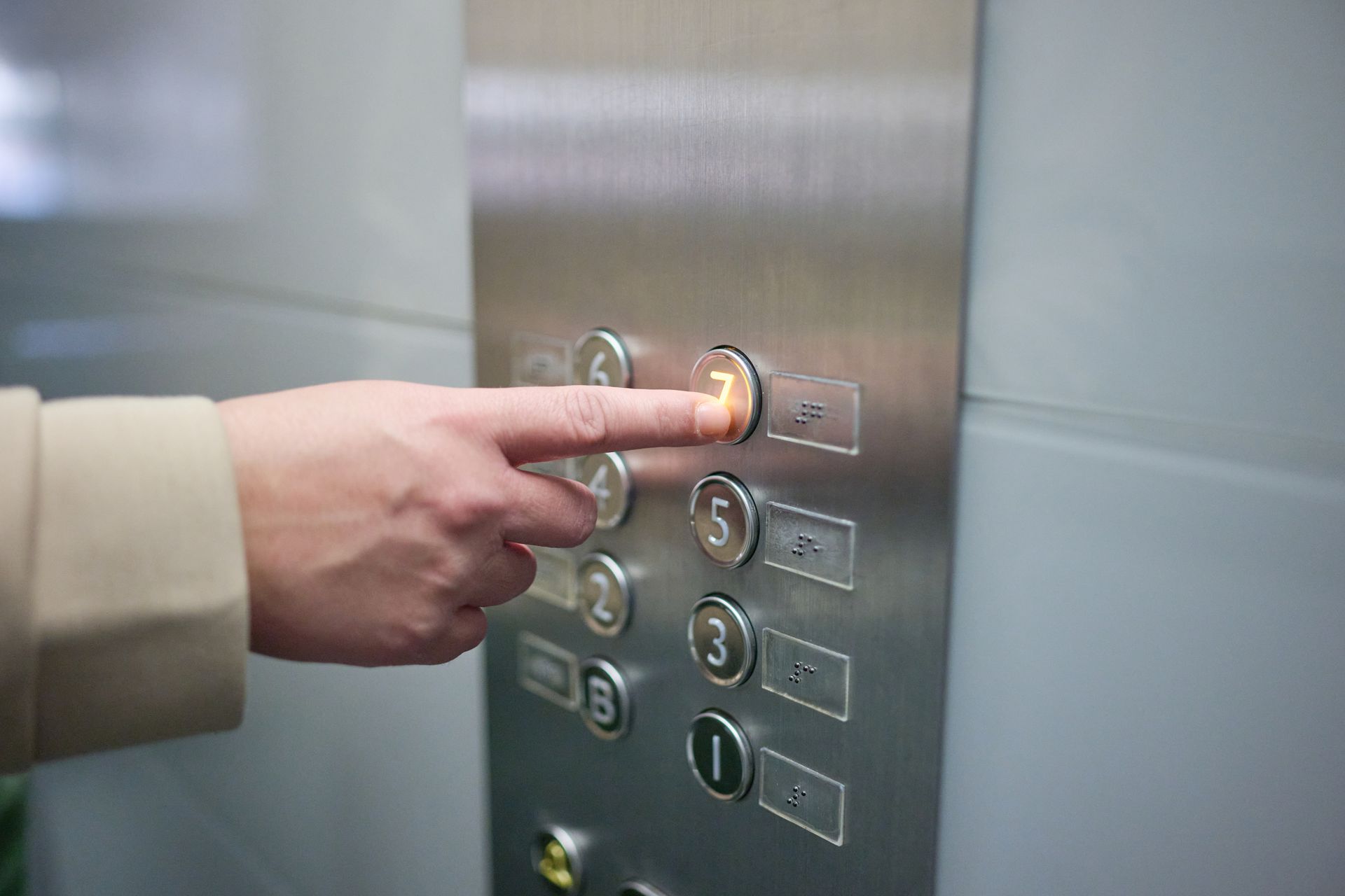 Person's finger pressing a lit button labeled Person's finger pressing a lit button labeled