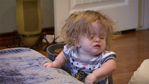 A little girl is sitting on a couch making a funny face.
