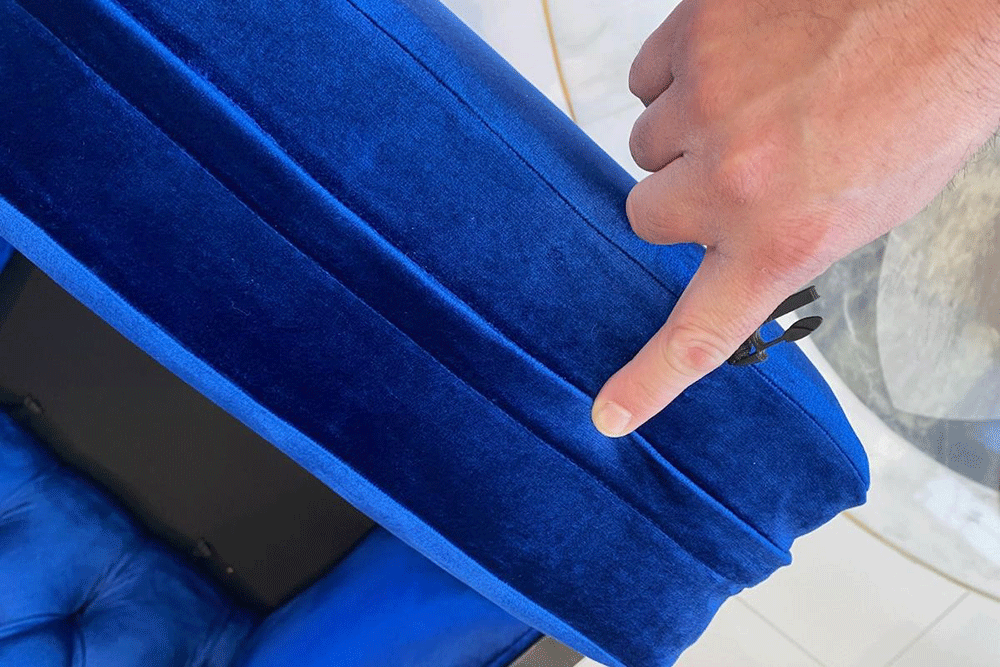 Two men are cleaning a couch in a living room.