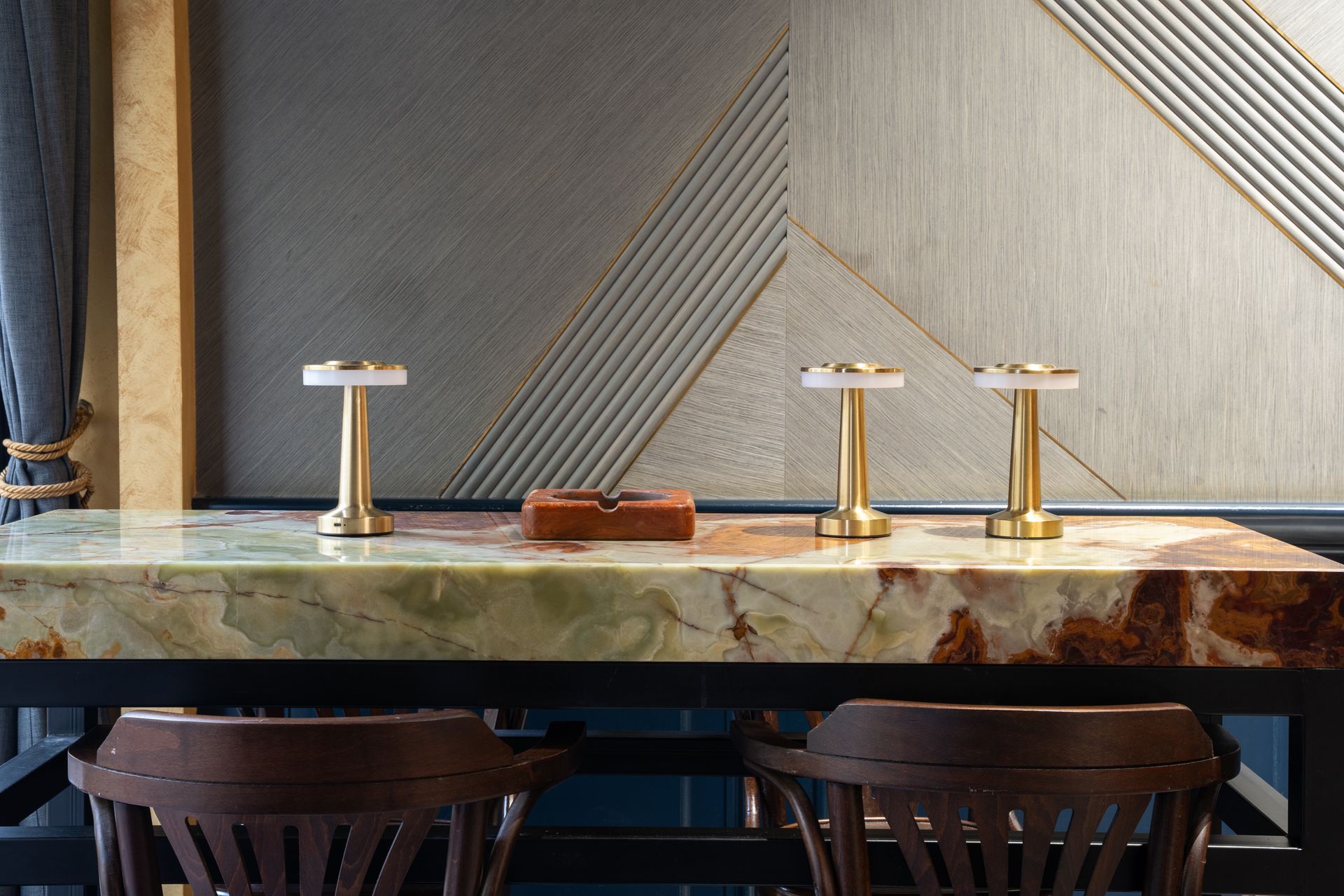 Marble bar counter with three brass table lamps and dark wooden stools in a modern interior Marble bar counter with three brass table lamps and dark wooden stools in a modern interior