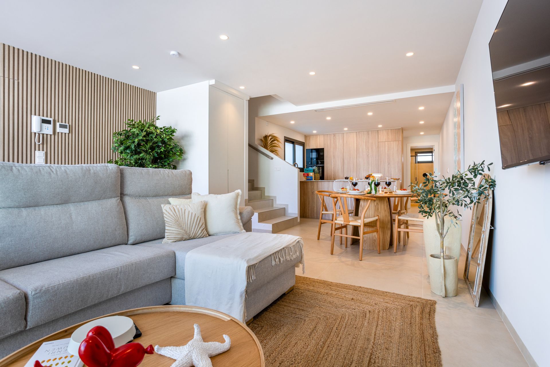 Bright modern living room with gray sofa, wooden dining area, and indoor plants Bright modern living room with gray sofa, wooden dining area, and indoor plants