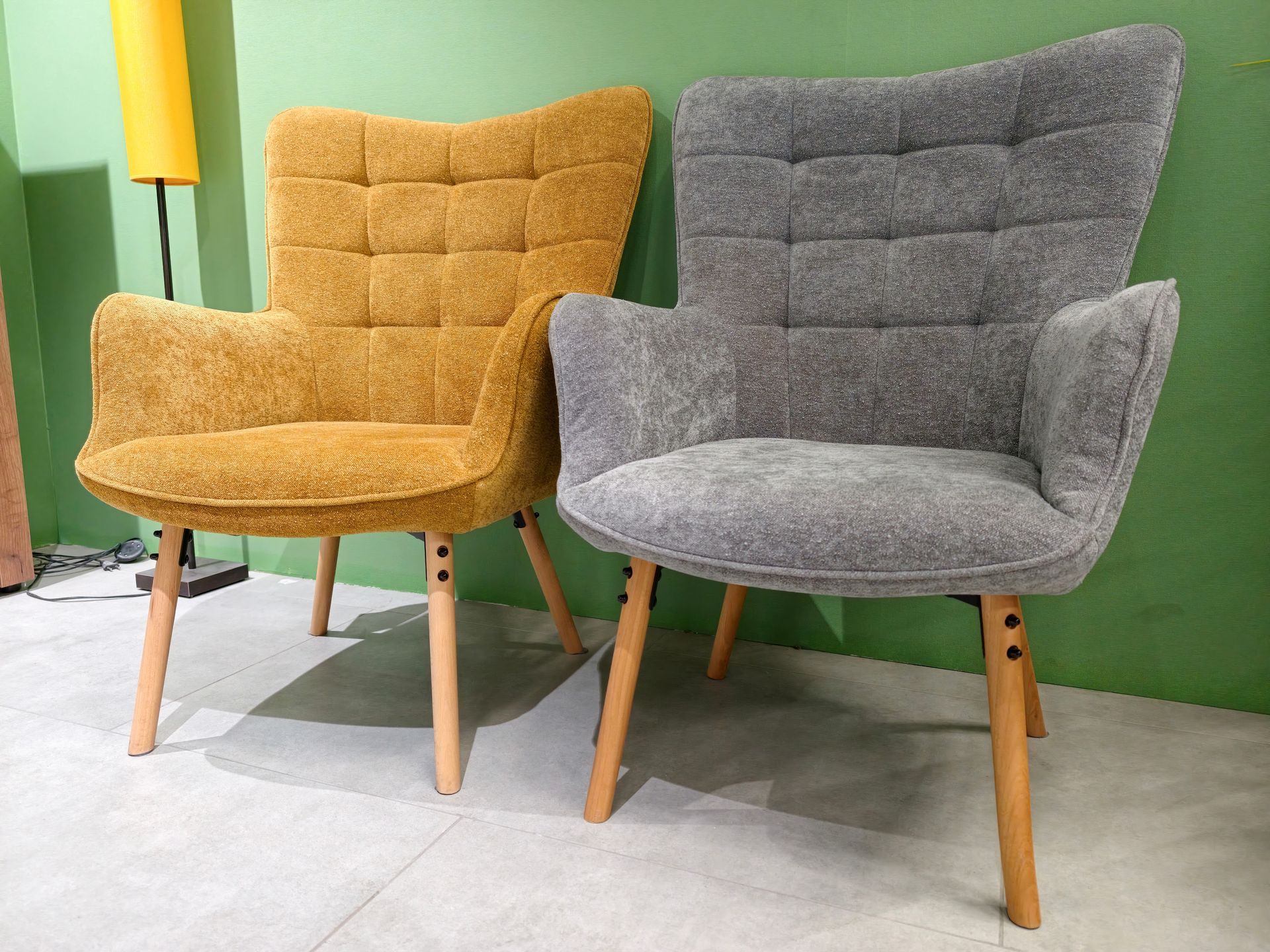 Two upholstered chairs, mustard yellow and gray, in a modern room against a green wall. Two upholstered chairs, mustard yellow and gray, in a modern room against a green wall.