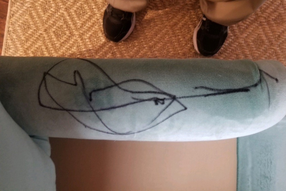 A person is standing next to a couch with a drawing on it.