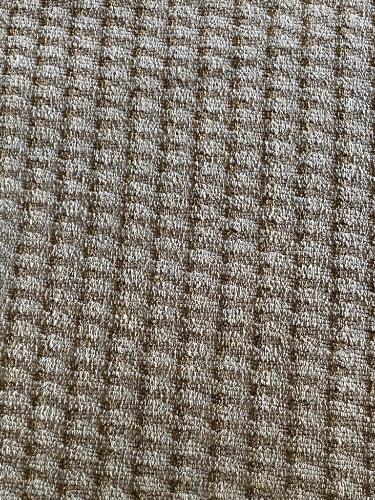 A close up of a brown and white carpet texture.