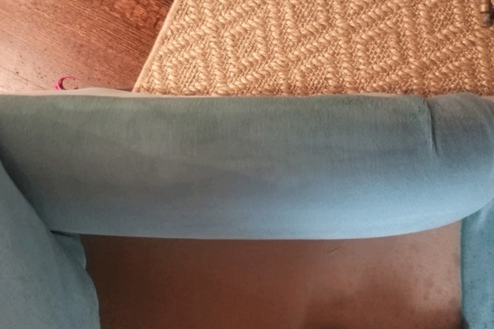 A blue couch is sitting on a wooden floor next to a rug.