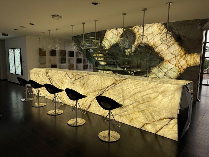 Modern bar with glowing stone counter and black stools in a sleek, dimly lit interior.