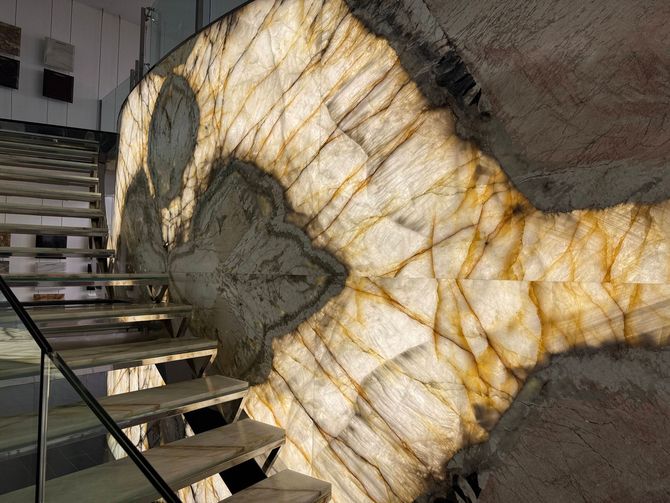 Sunlit stone wall with a glowing amber-veined rock beside a staircase and railing