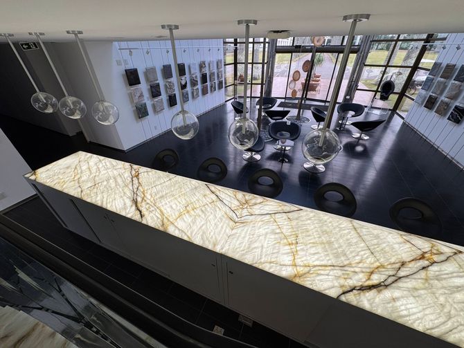 Modern showroom with large windows, hanging rings, and a marble reception counter