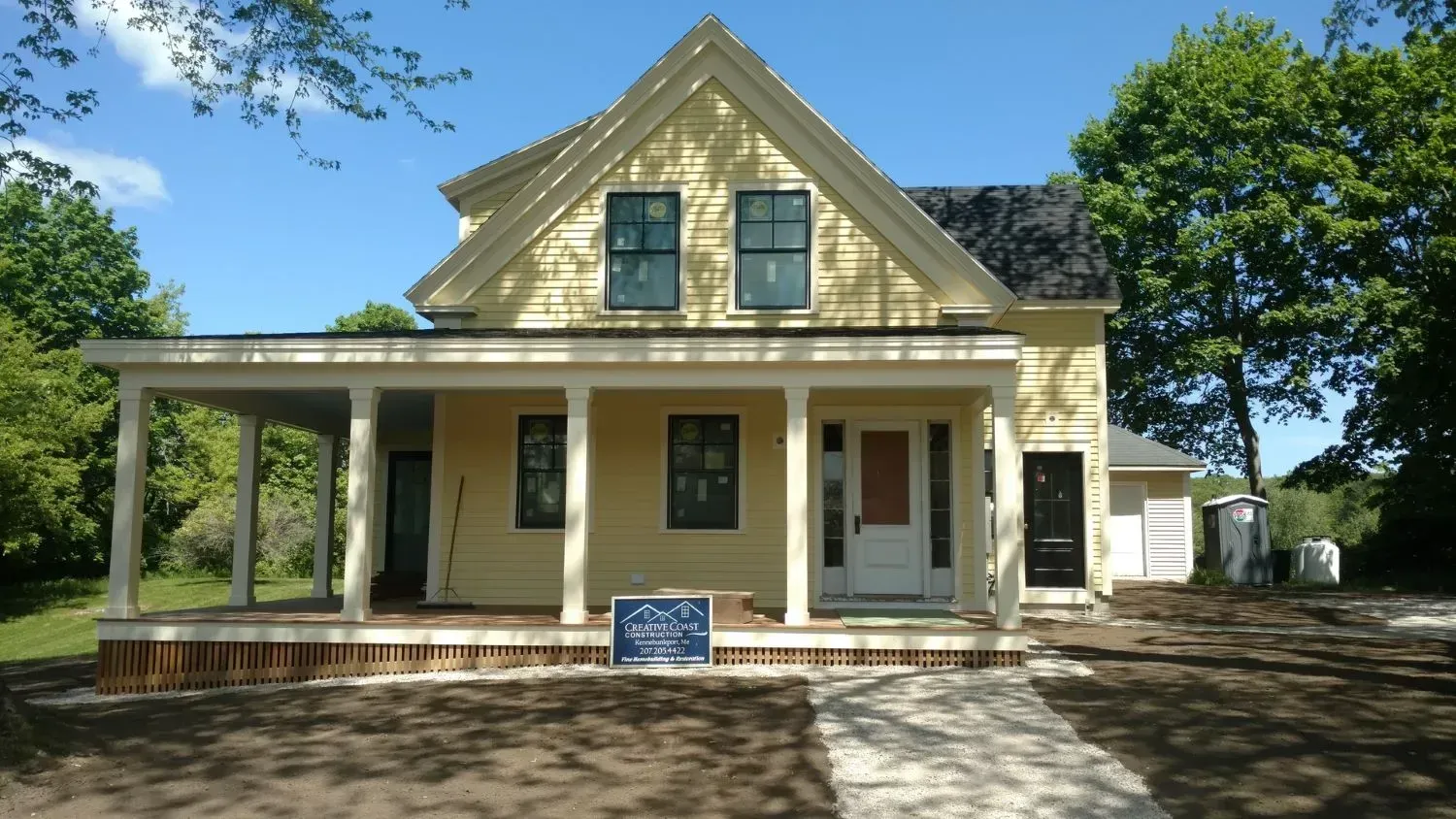A yellow house with a porch and a sign that says