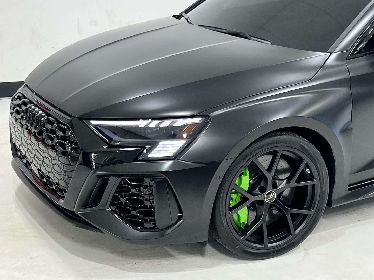 A close up of a black car with green brake calipers.