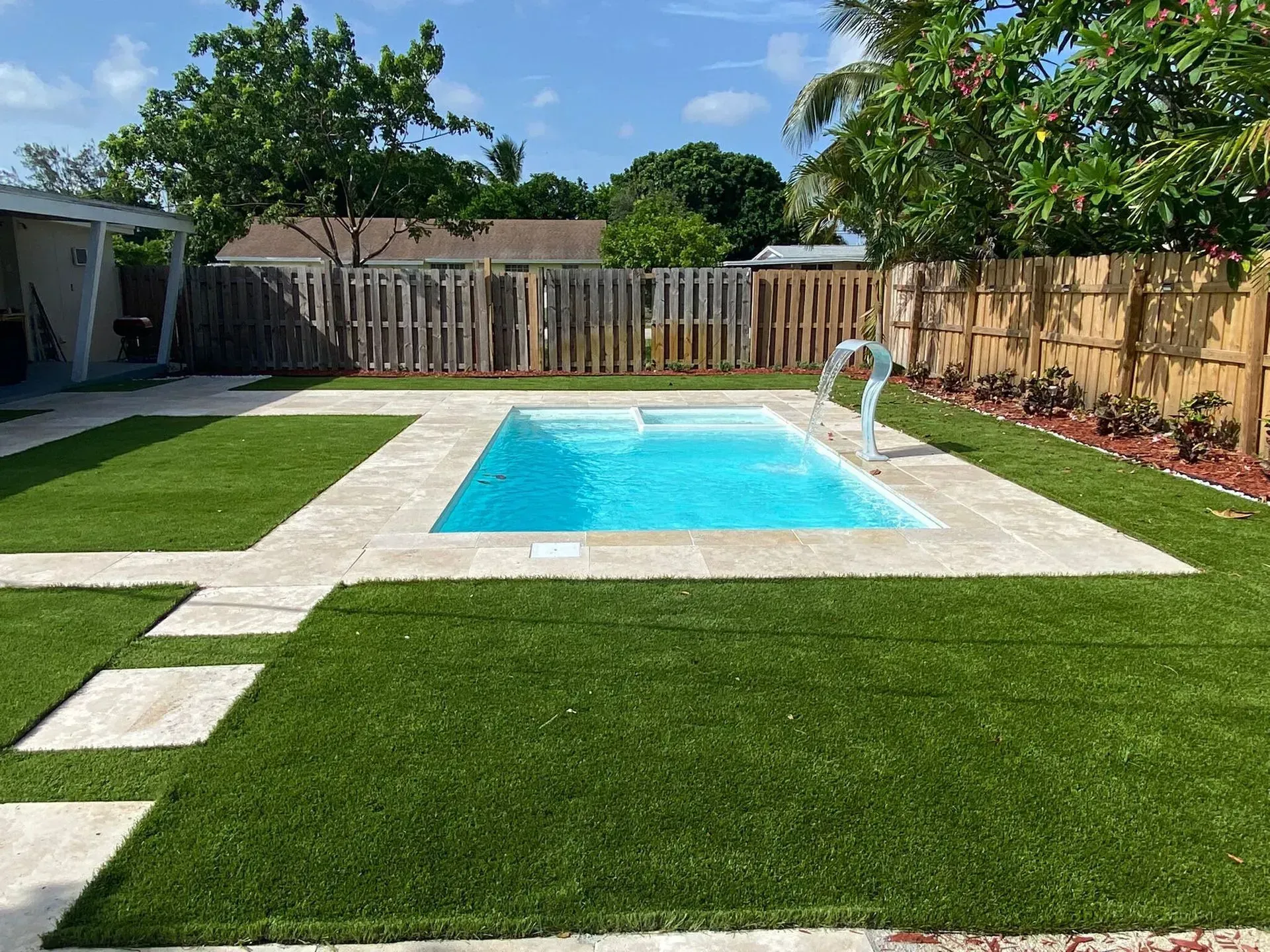 A swimming pool in the middle of a lush green backyard.