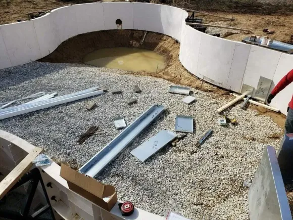 A man is standing in front of a swimming pool being built.