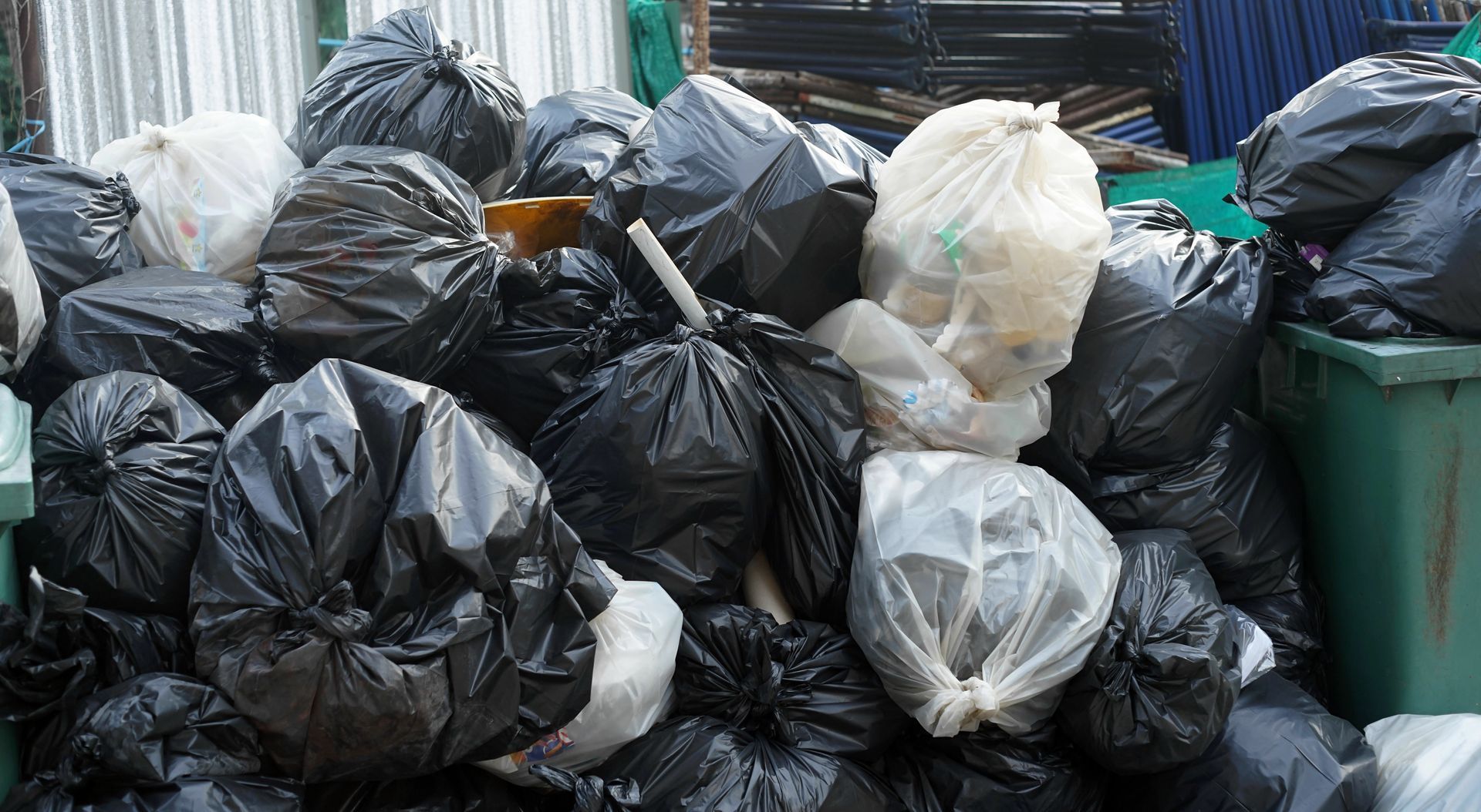 A pile of black and white garbage bags in a dumpster.
