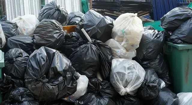 A pile of black and white garbage bags in a dumpster.