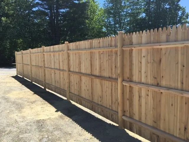 A wooden fence is sitting on the side of a road.