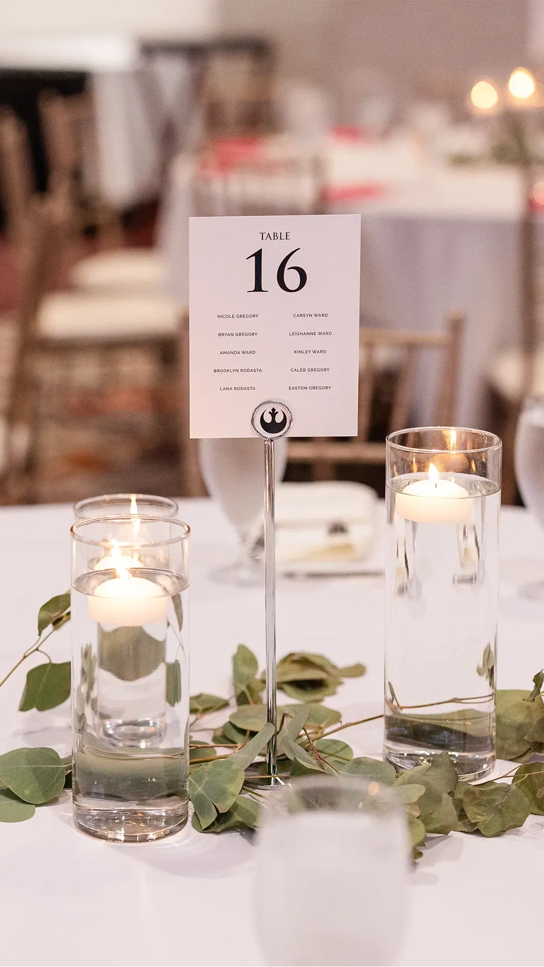 Table centerpiece with candles, greenery, and a table number card reading 16.