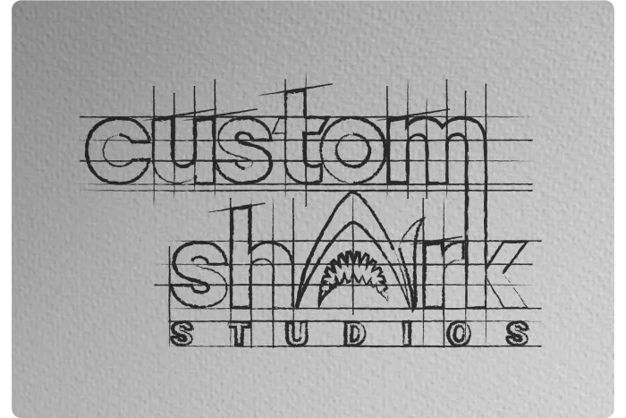 “custom shark studios” logo in black line art with a shark fin shape over the word “shark”