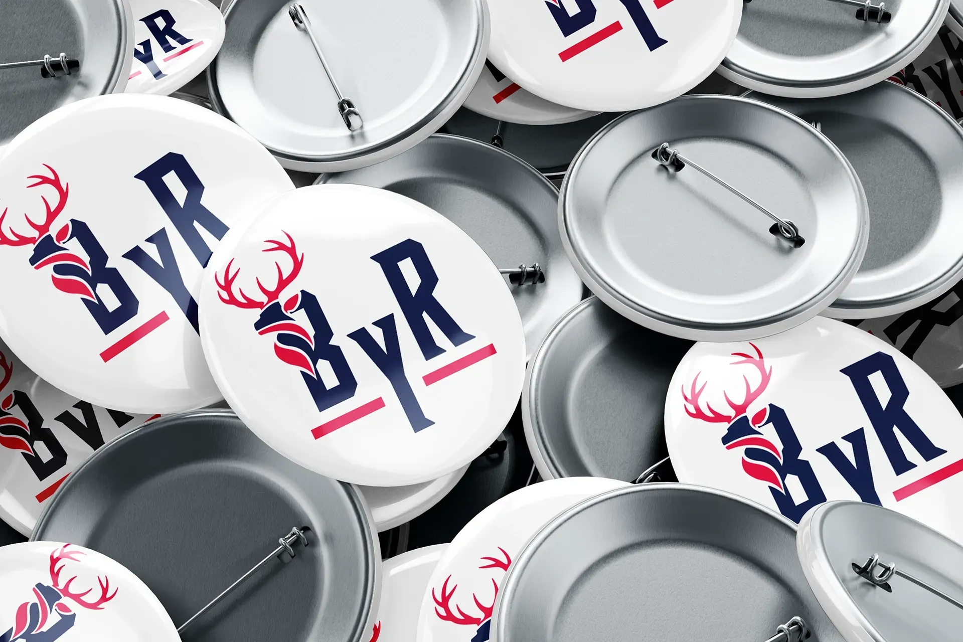 Assorted white and gray button pins with red and blue deer-logo designs scattered together