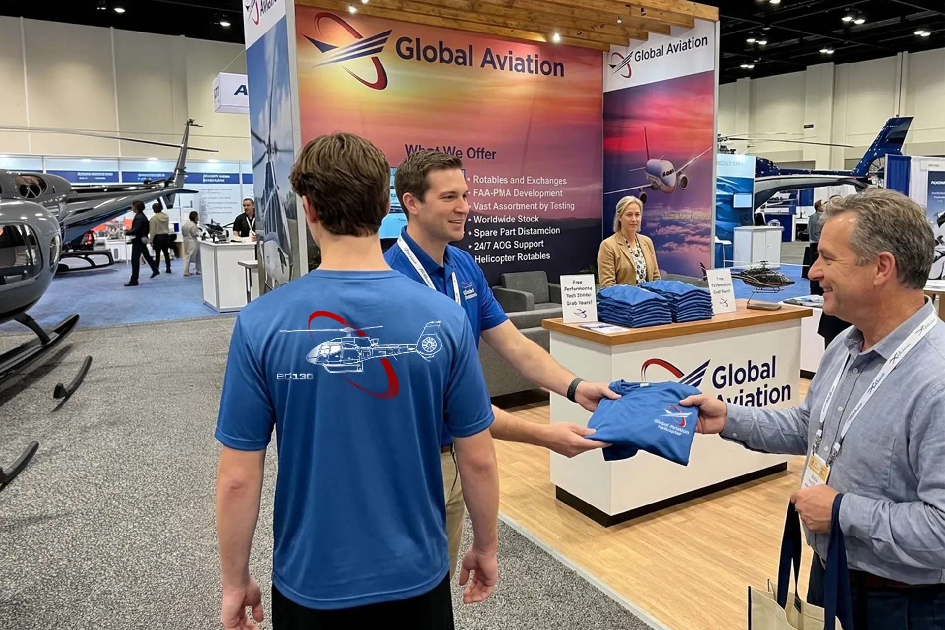 People at a Global Aviation booth at a trade show, discussing blue branded items.