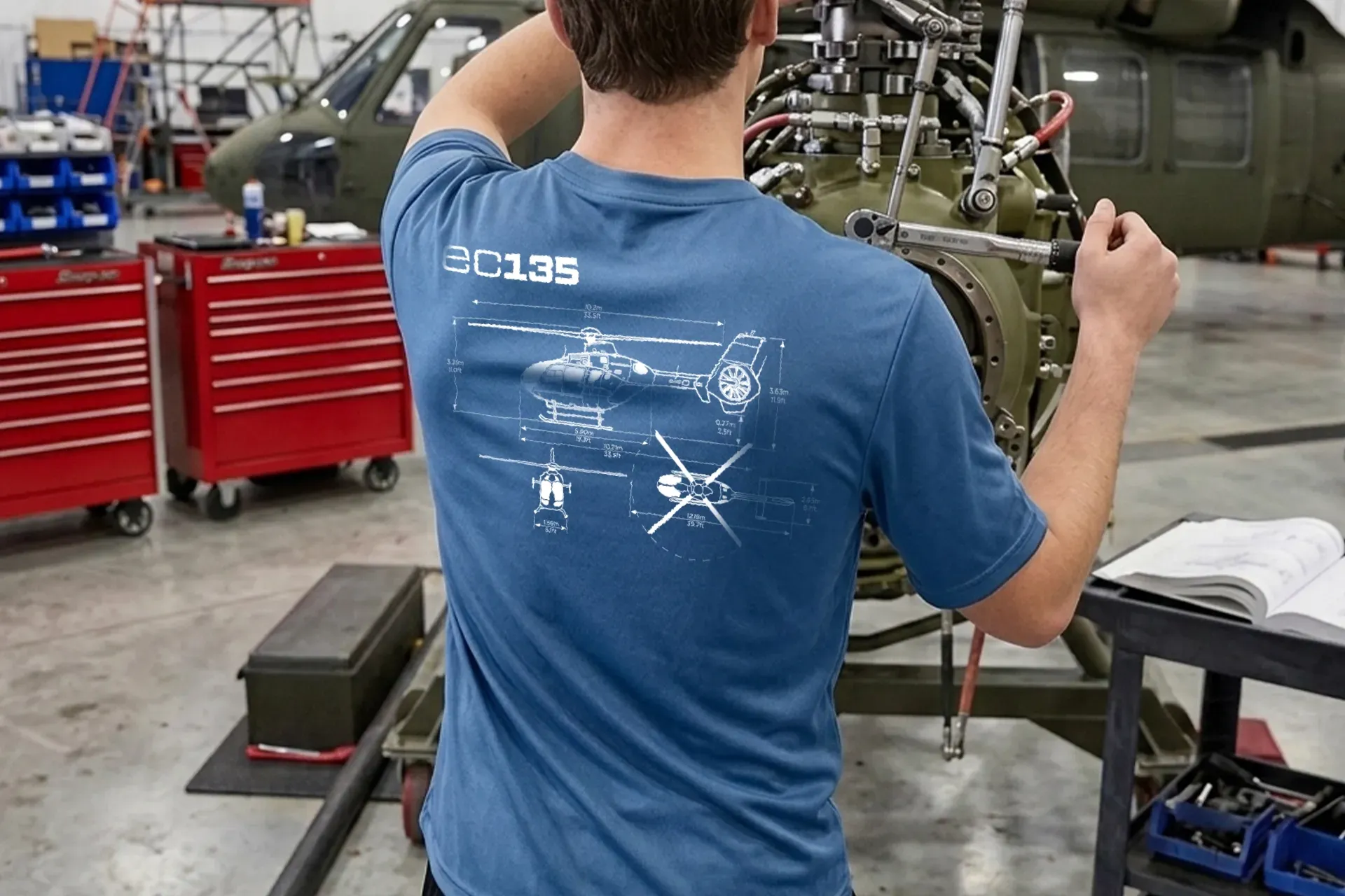 Person working on a mechanical assembly in a workshop, wearing a blue shirt near red tool cabinets.