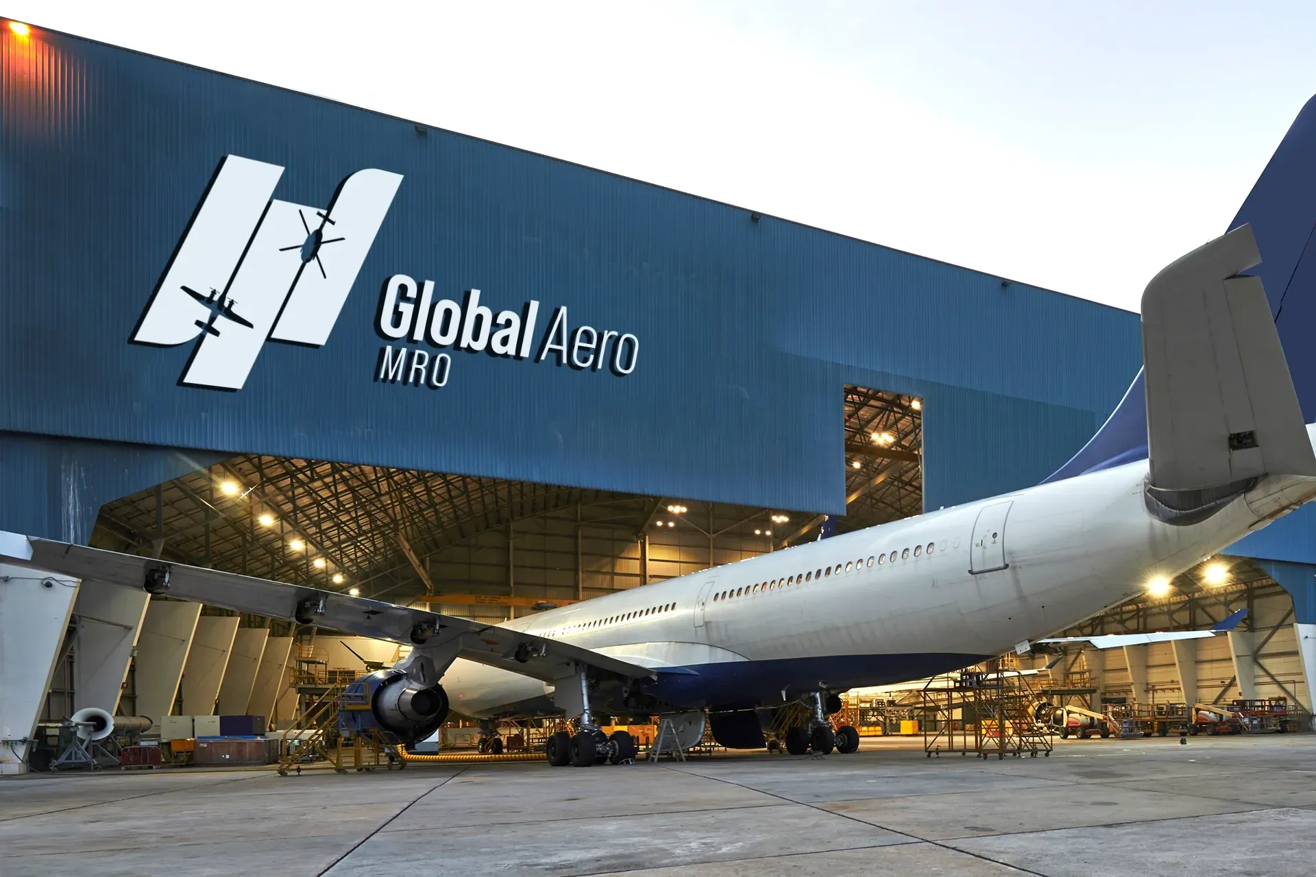 GlobalAero hangar at dusk with a large white airplane parked outside and inside lights glowing