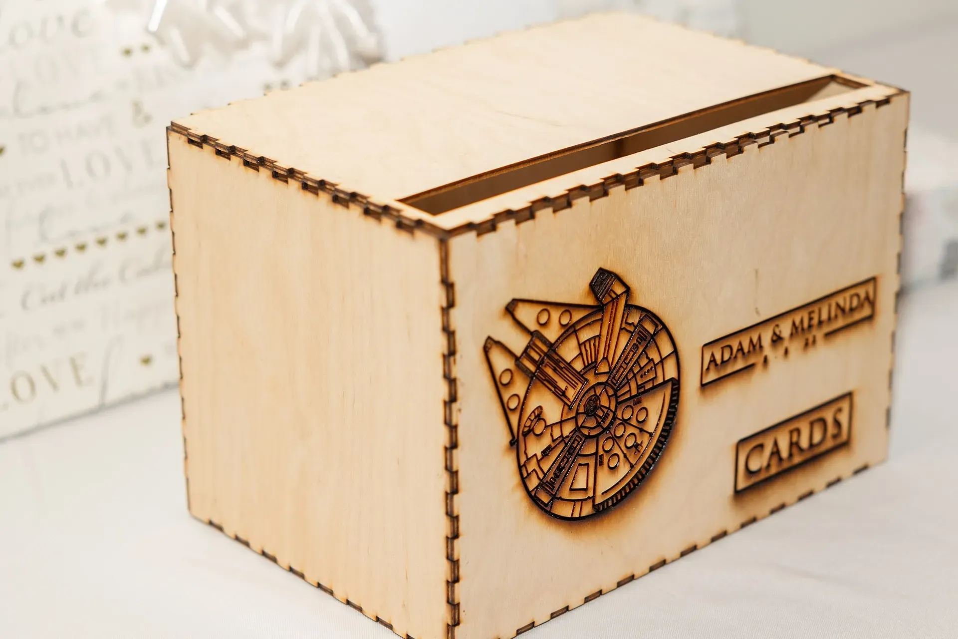 Laser-cut wooden card box with engraved airplane and labels on a light background