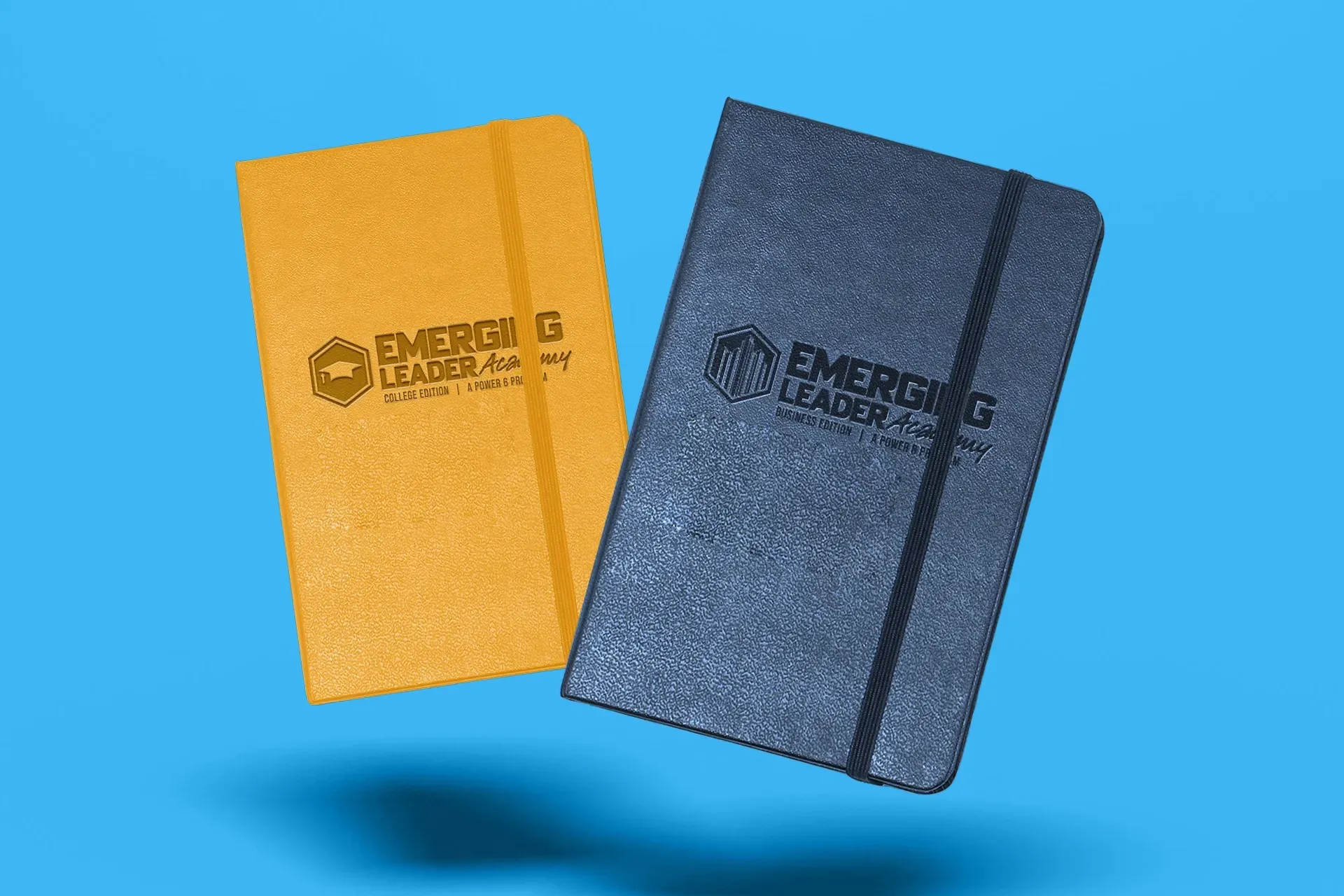 Two branded pocket notebooks, one yellow and one dark blue, on a blue background