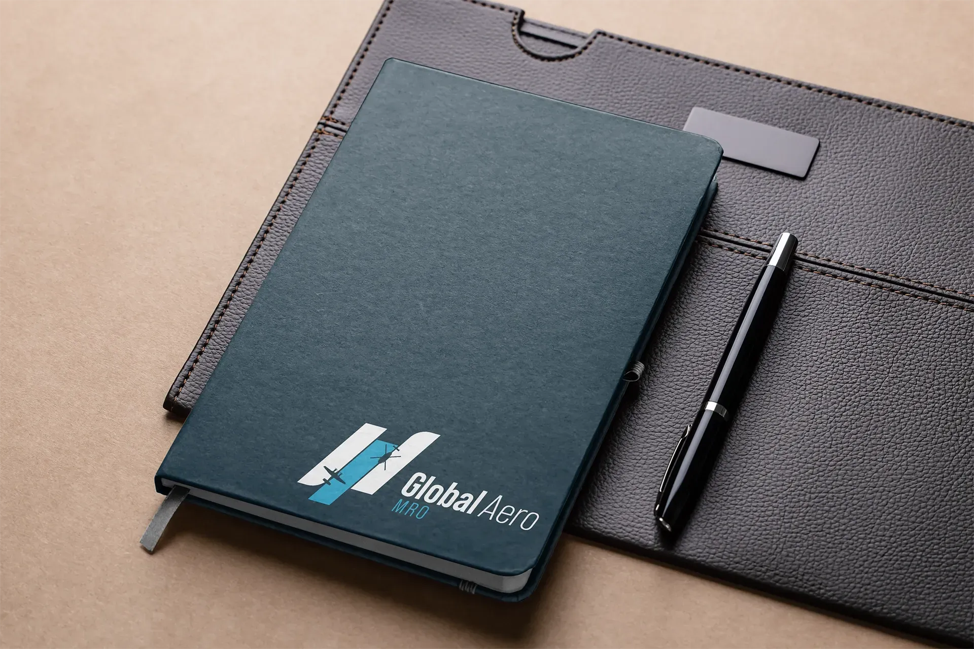 Dark teal notebook and black pen on a gray fabric organizer pouch
