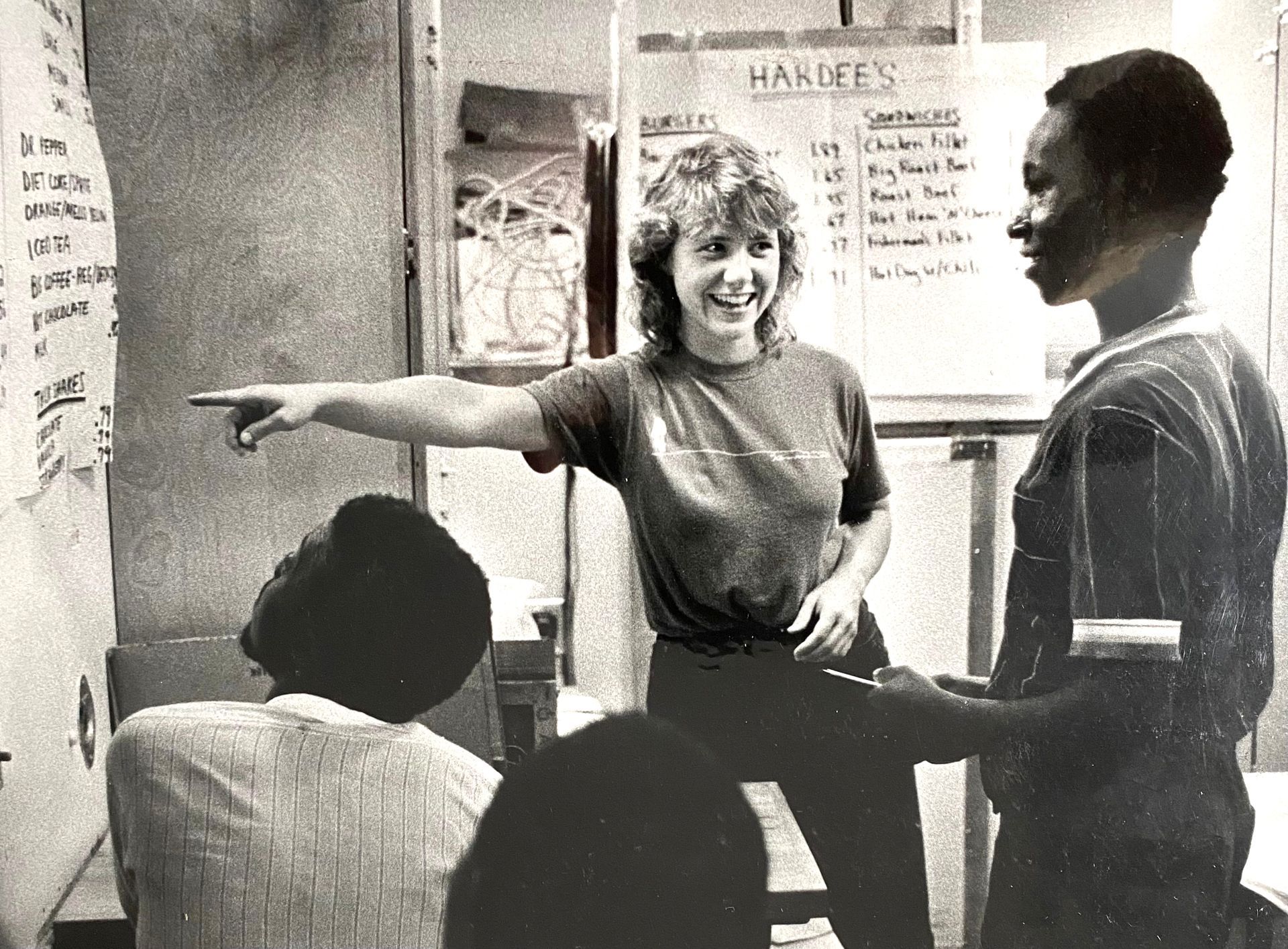 Woman pointing and smiling at a man in a classroom or office setting