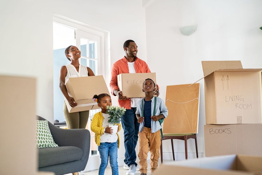 Family carrying moving boxes into a bright living room