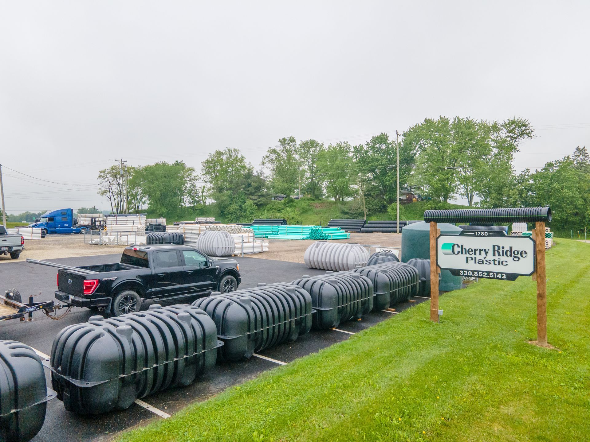 A row of black tanks and a pickup truck parked near a sign for 