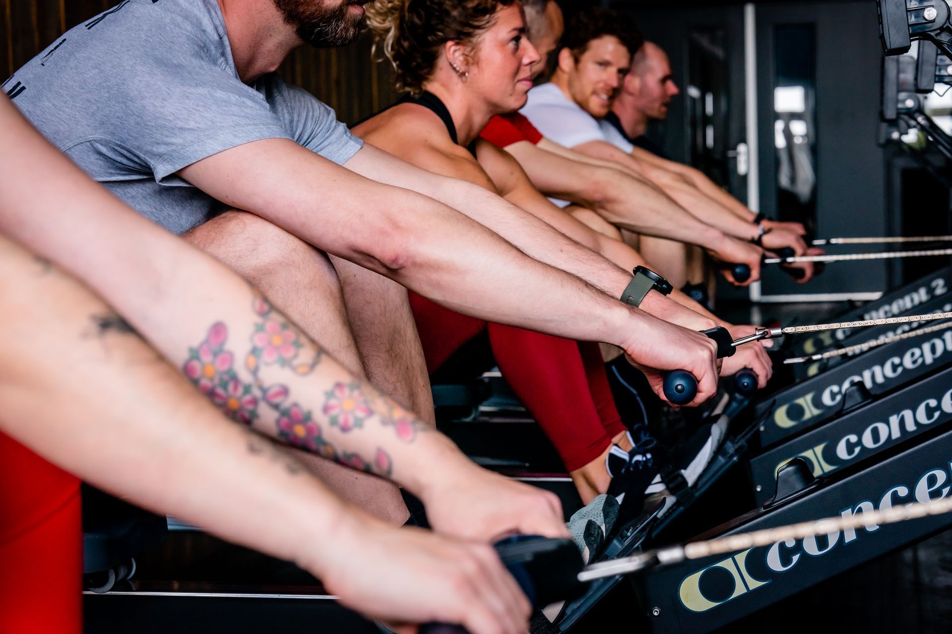 Mensen die trainen op roeimachines in een sportschool. Armen die aan de handgrepen trekken.