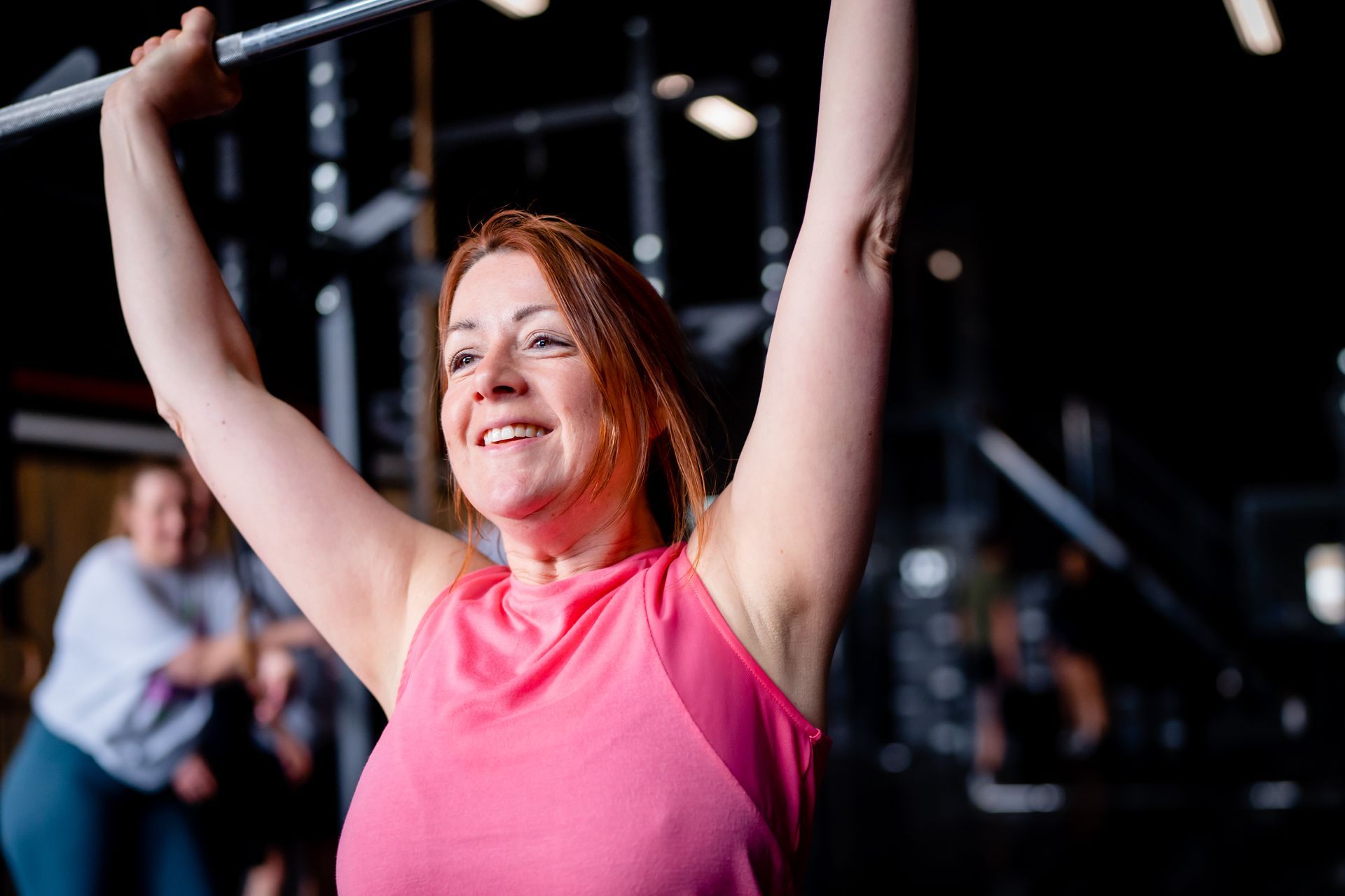 Een vrouw tilt een halter boven haar hoofd in een sportschool.