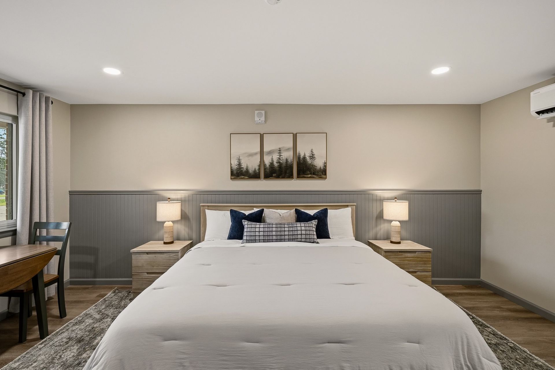 Cozy bedroom with wood ceiling, bed, orange lamp, and large glass doors opening to a sunny patio