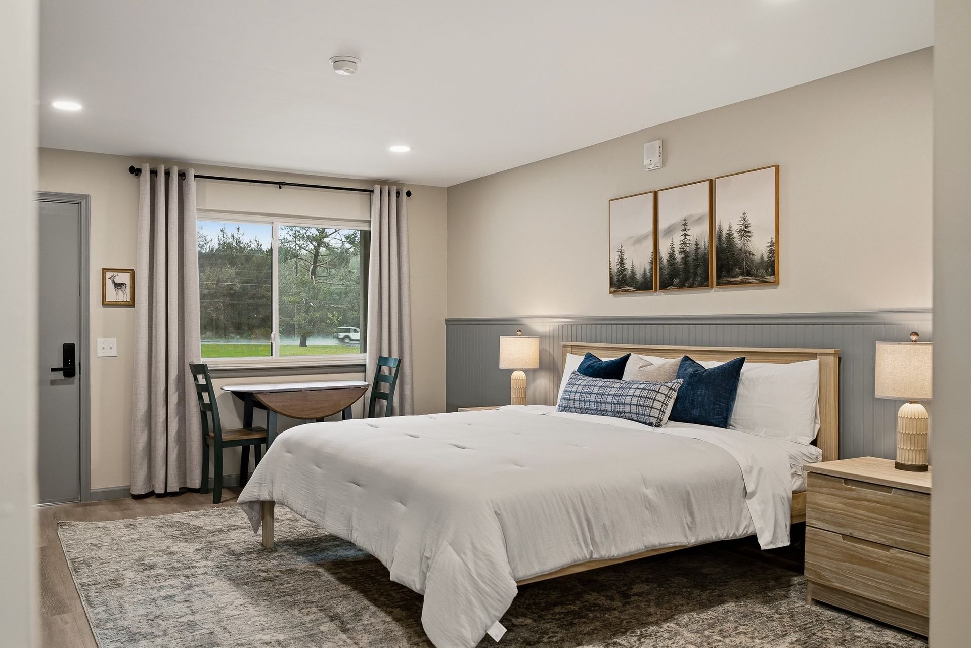 Cozy attic bedroom with a white bed, wood paneling, striped drapes, and a window letting in soft light