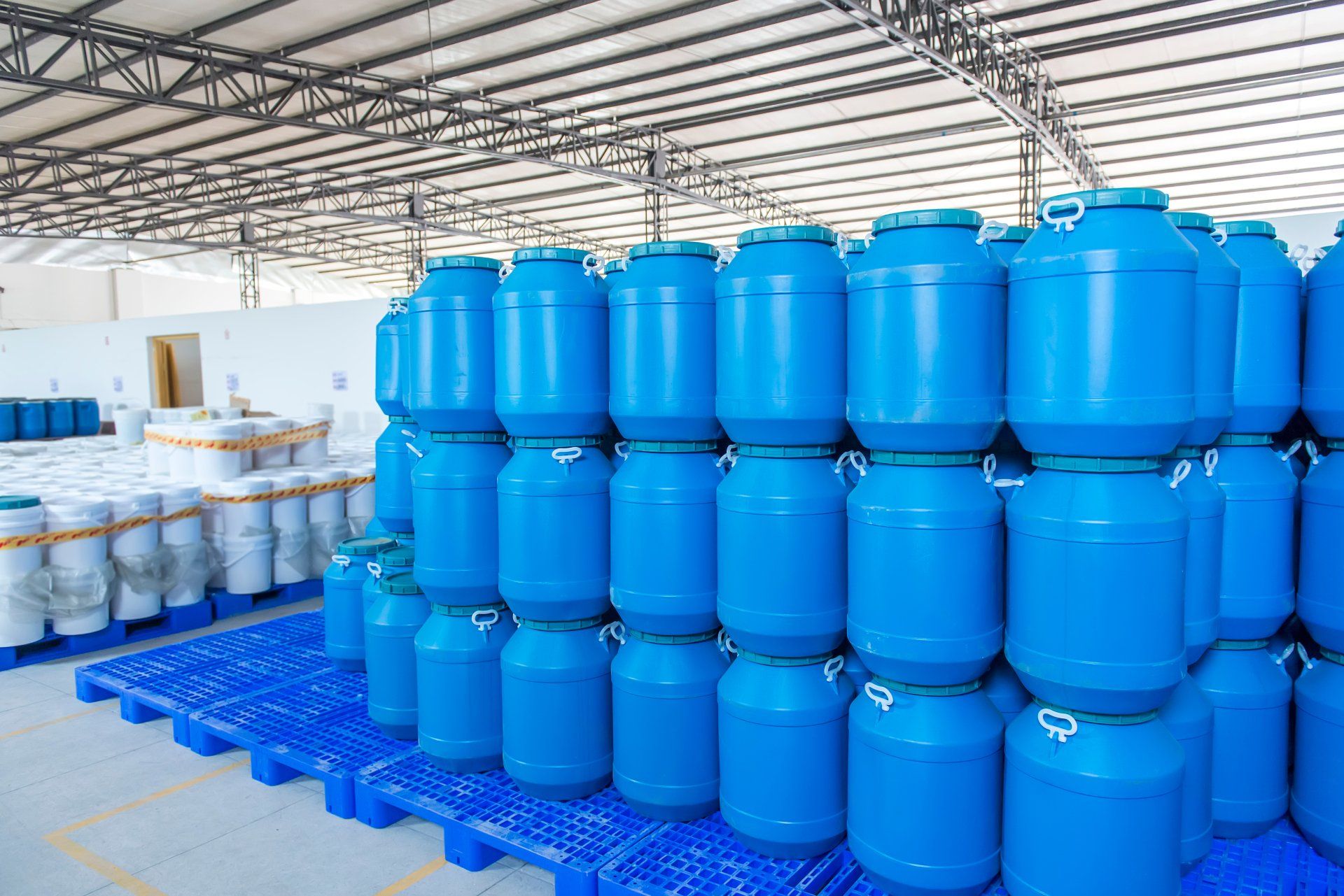 A warehouse filled with lots of blue barrels stacked on top of each other.