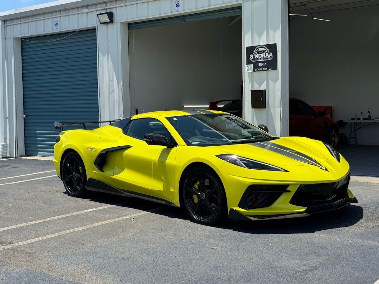 Yellow Corvette sports car parked outside a garage.