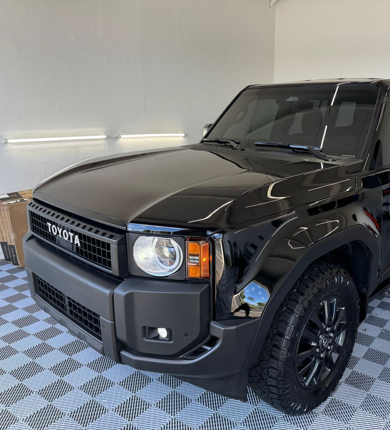 Black Toyota SUV, front view, inside a garage, with a matte black front bumper and black tires.