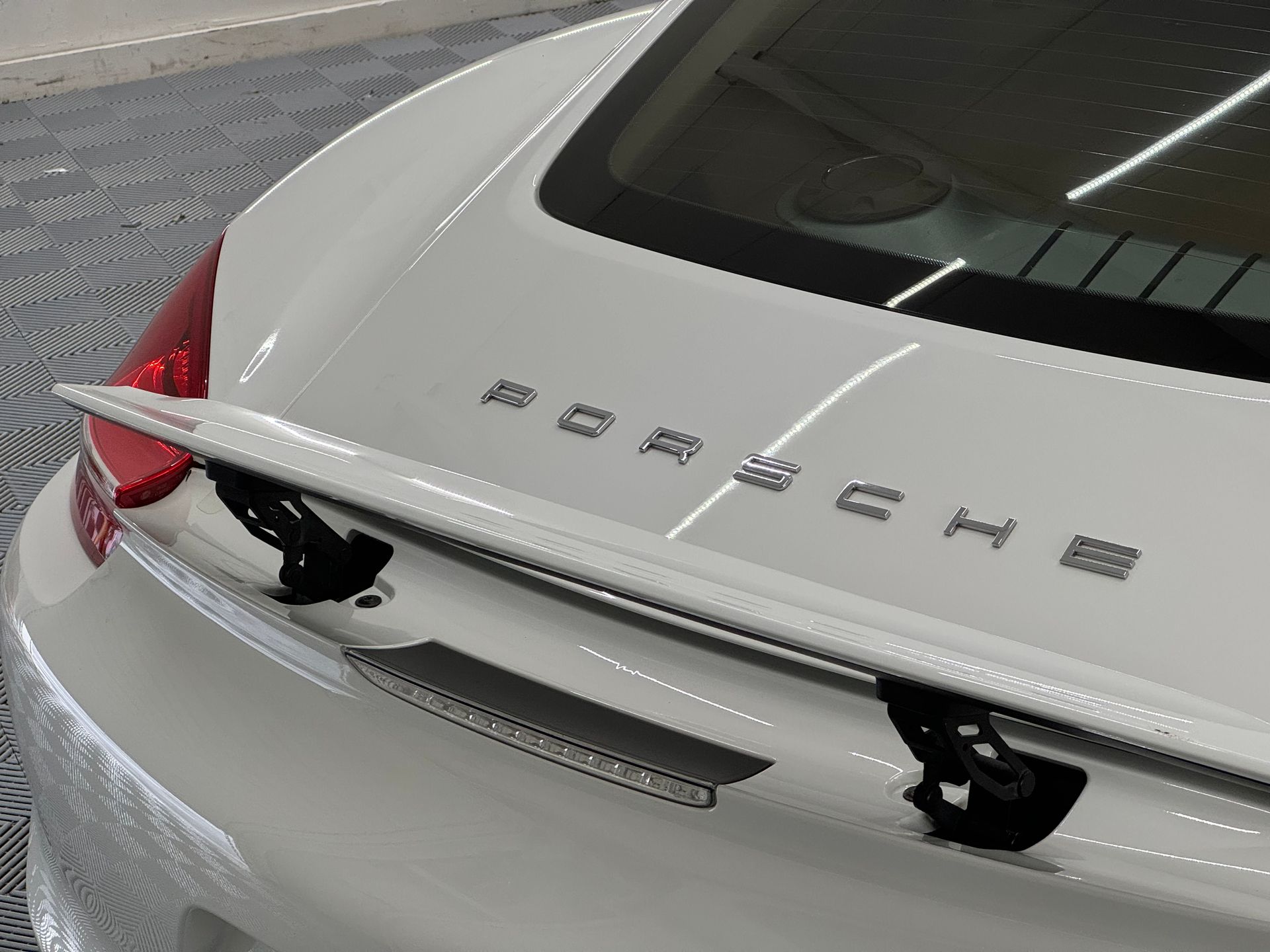 White Porsche car rear with a spoiler; the brand name is visible.