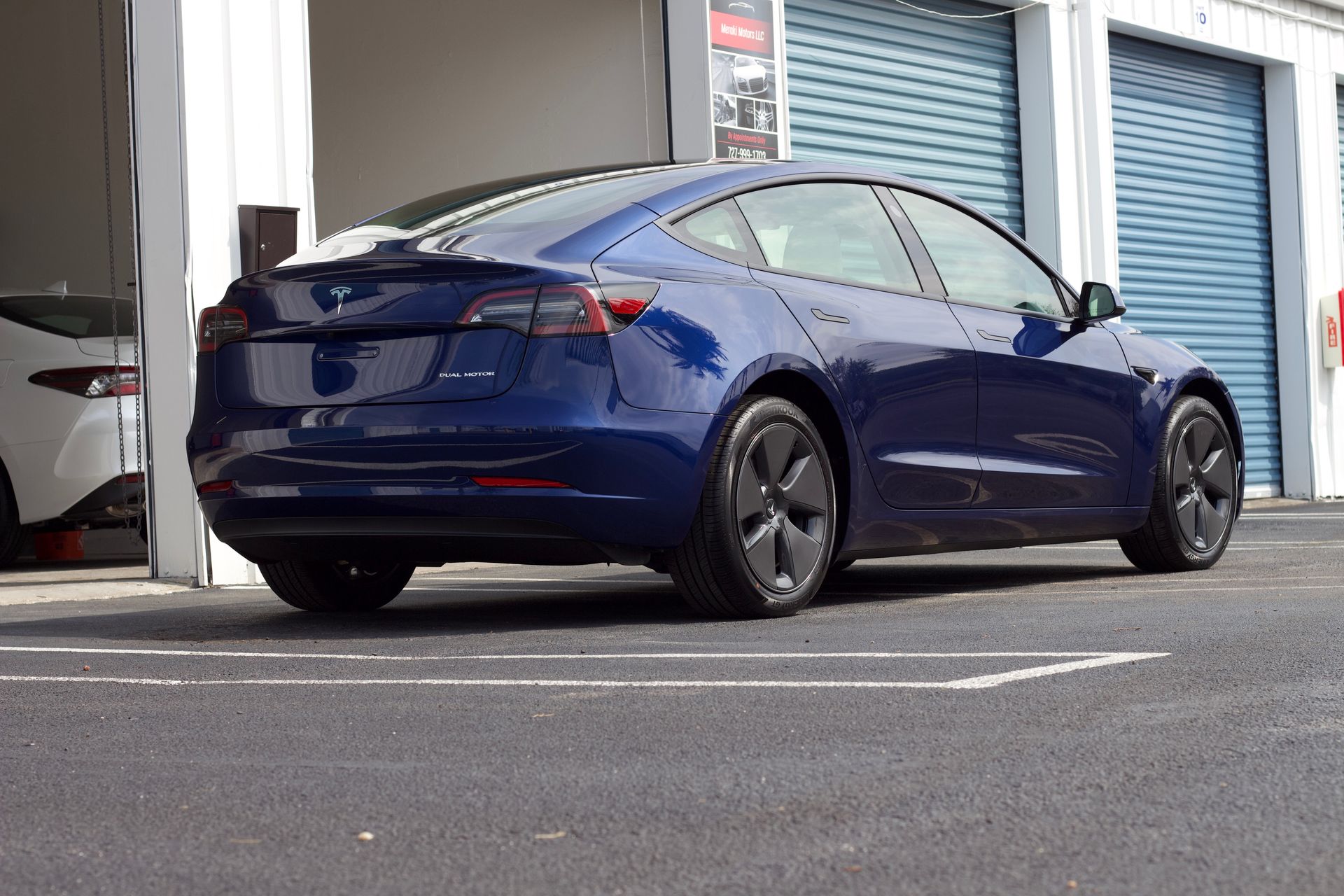 Blue Tesla Model 3 car parked outside a building.