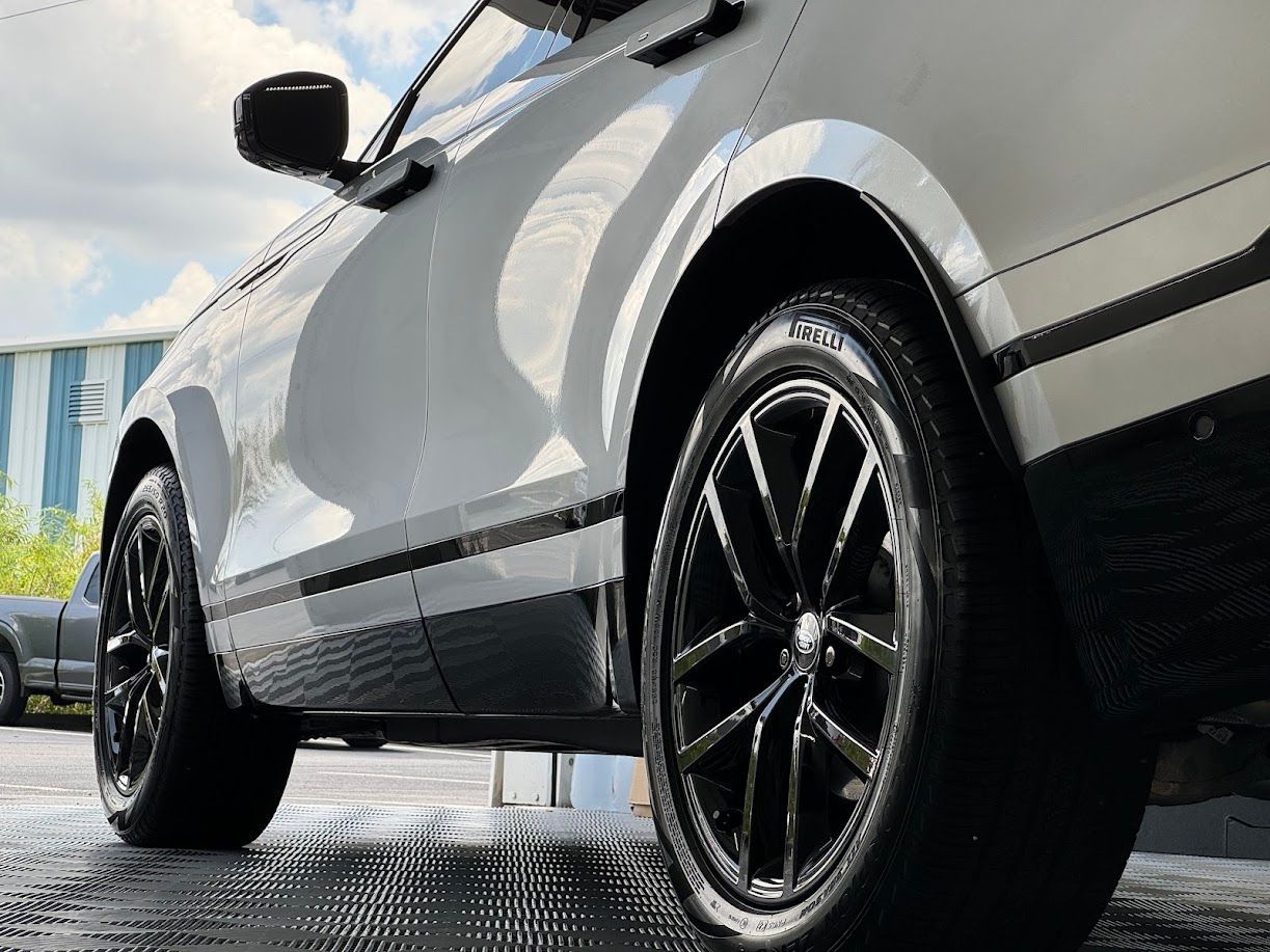 White SUV with black wheels, low angle view. Shiny finish, parked outside.