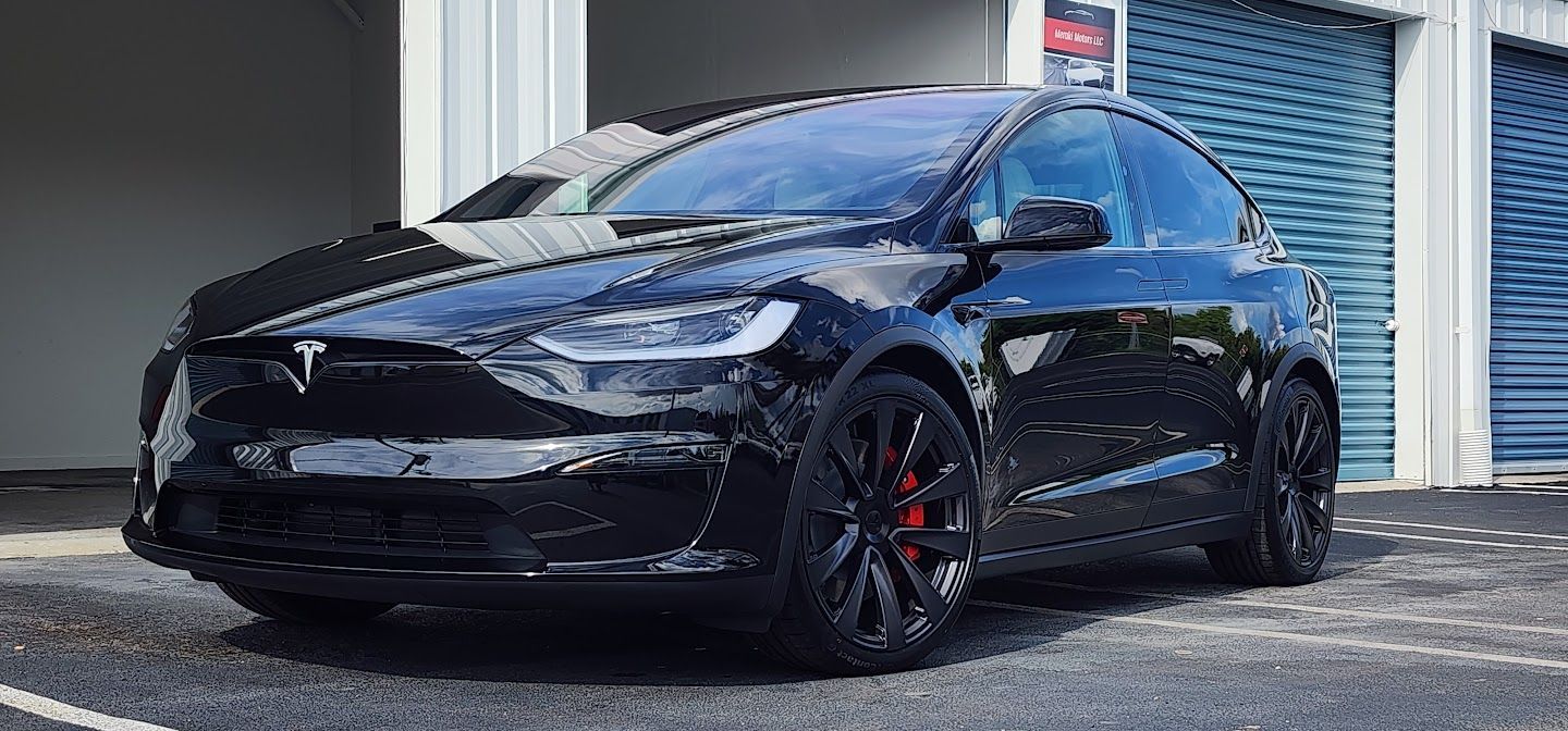 Black Tesla Model X parked outside, with red brake calipers.