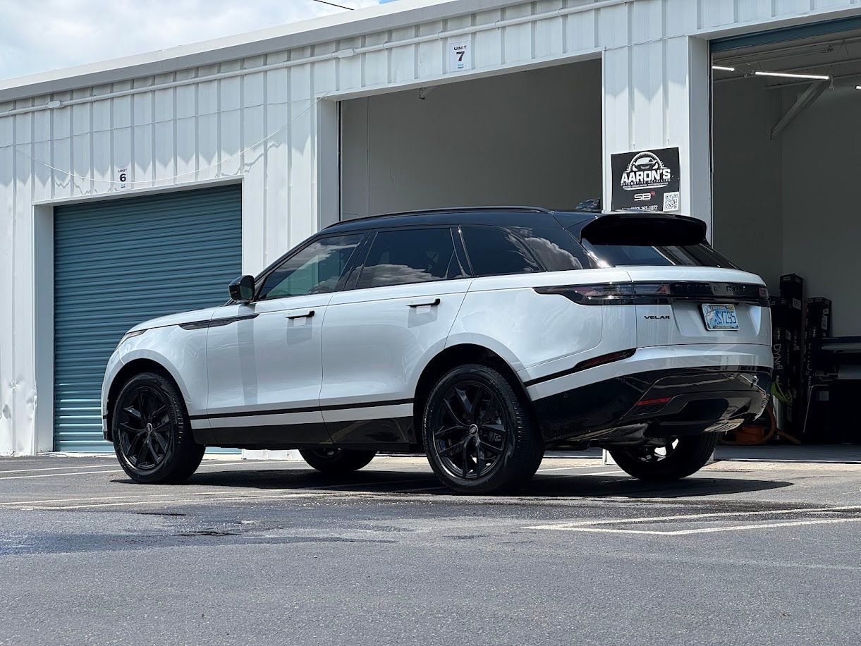 White Range Rover SUV with black accents parked in front of a building with garage doors.
